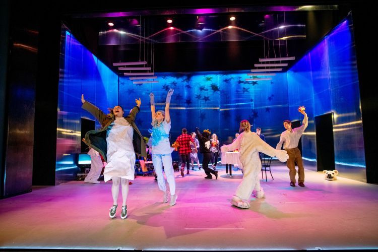 Actors dance in a circle on stage